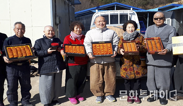 법륜스님이 마을주민들과 곶감을 들고 있다