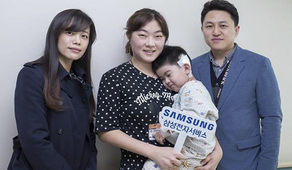 삼성전자서비스의 후원으로 인공달팽이관 수술을 받은 아동과 어머니(가운데)를 격려 방문한 사랑의달팽이 재단 관계자(왼쪽)와 오지상 삼성전자서비스 한마음협의회 대표위원(오른쪽)이 기념 사진 촬영을 하고 있다. (출처 : 삼성전자서비스)